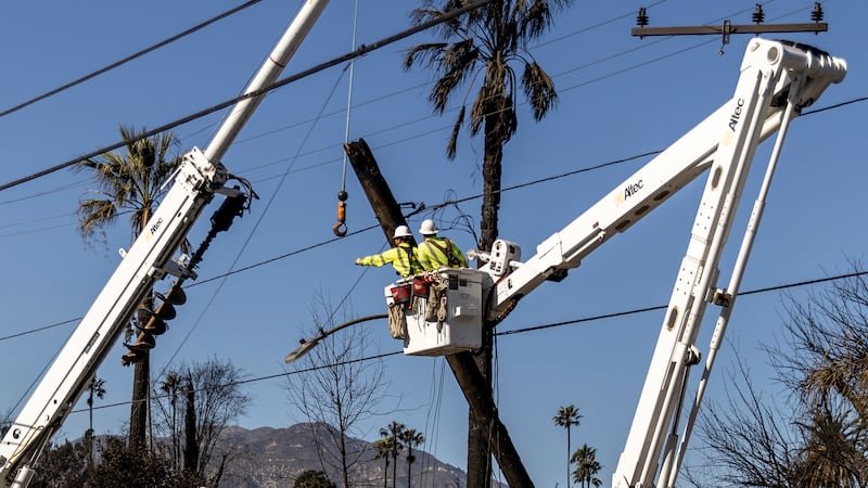 Workers with Southern California Edison remove a utility pole damaged by the Eaton Fire in...