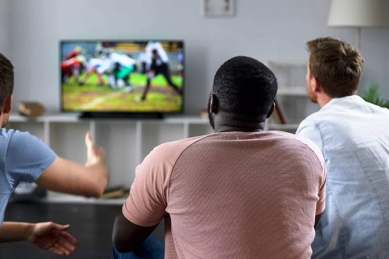 NextGenTV Sports - Male friends gather to watch football competition on big screen, sofa experts