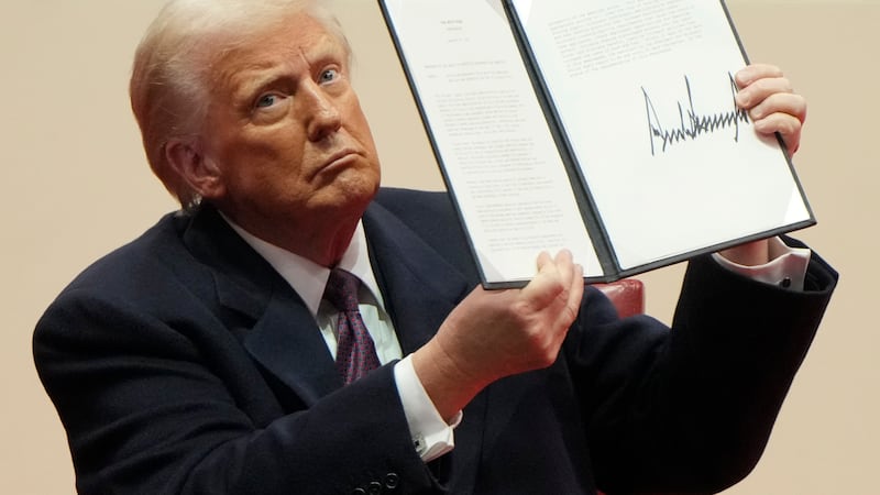 President Donald Trump holds up an executive order after signing it at an indoor Presidential...