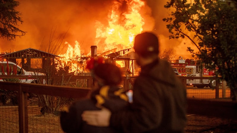 People watch as the Eaton Fire engulfs a structure Wednesday, Jan. 8, 2025, in Altadena,...